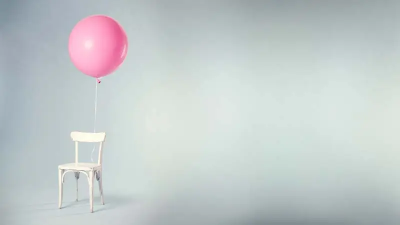 Pink balloon tied to chair in empty space